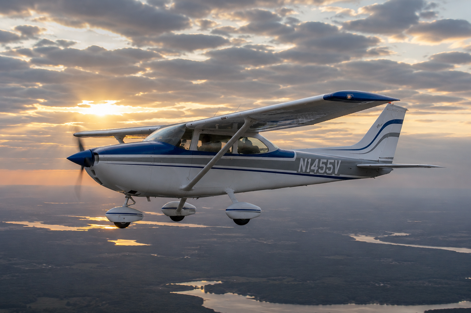 Cessna 172 flying against a sunset sky with clouds.